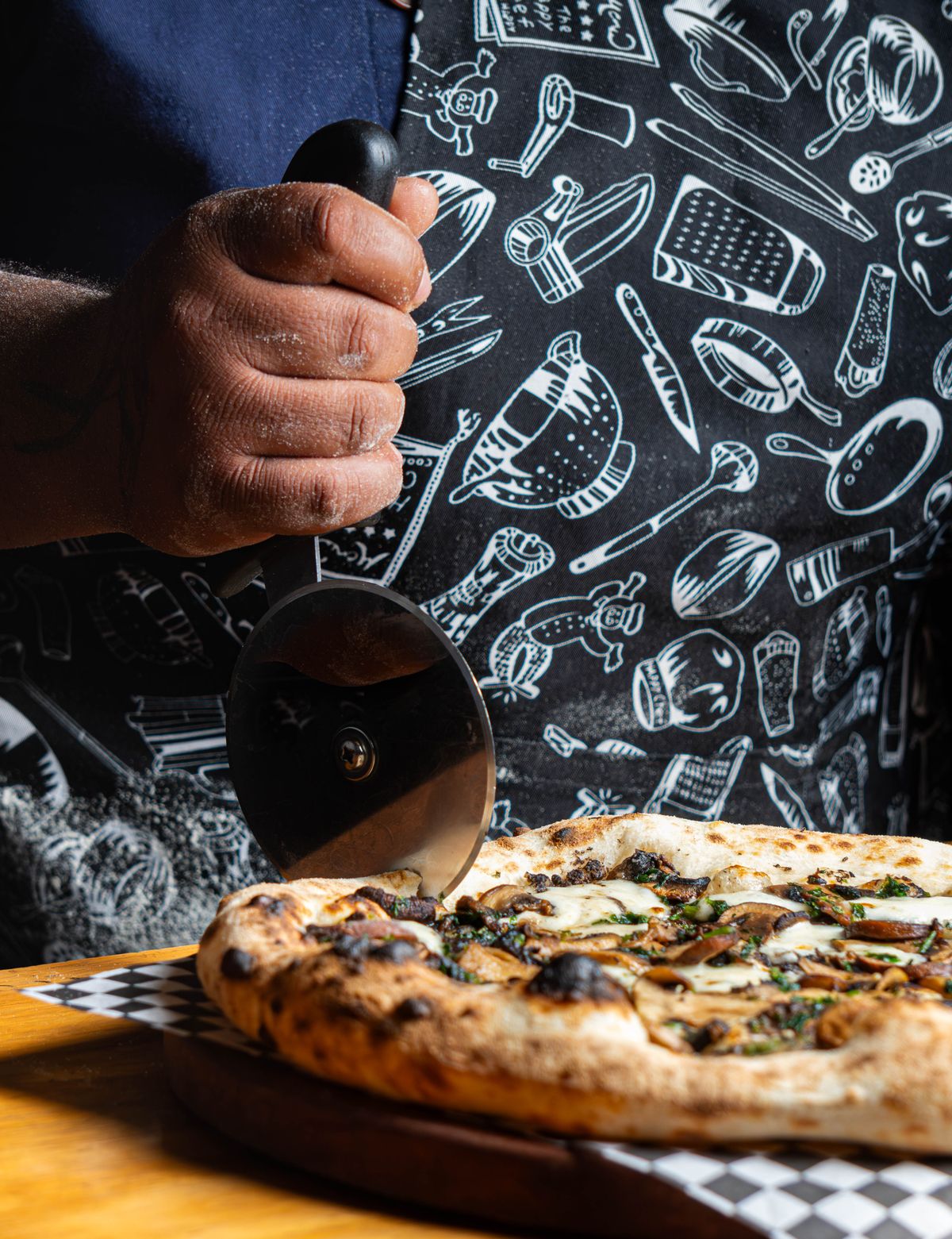 Pizzaiolo cortando uma pizza artesanal